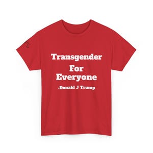 May include: Red t-shirt with the text "Transgender For Everyone" and "-Donald J Trump" in white. The shirt has short sleeves and a crew neck. The image is a close-up of the shirt.