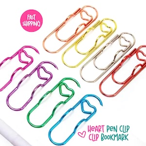 Puede incluir: Una colección de clips de papel en forma de corazón de varios colores, incluyendo rosa, morado, verde, azul, dorado, plateado y rojo. La imagen también incluye el texto "Heart Pen Clip Clip Bookmark".