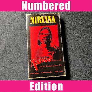 Könnte beinhalten: Eine rechteckige VHS-Kassettenhülle mit einem schwarz-roten Grafikdesign. Das Cover zeigt den Text NIRVANA in Gelb, Tango in Rot und Live At Buenos Aires, 92. Es sind die Namen Kurt Cobain, Krist Novoselic und Dave Grohl aufgeführt.
