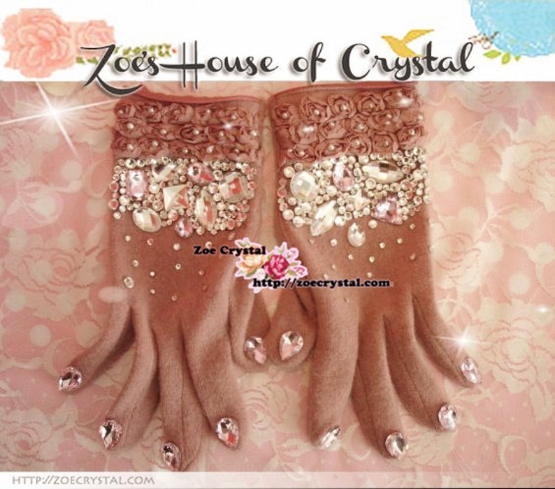 May include: A pair of brown fingerless gloves with a rose-shaped design and embellished with rhinestones. The gloves have a pink and white floral pattern on the back of the hand. The text "Zoe's House of Crystal" is visible at the top of the image.