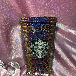 May include: A reusable, iridescent,  tumbler covered in rhinestones with a Starbucks logo and the text "Old Soul" on the front.
