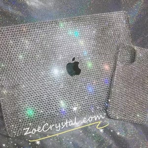 May include: A silver laptop and phone case covered in rhinestones. The laptop has the Apple logo in the centre. The text "ZoeCrystal.com" is visible in the bottom right corner.