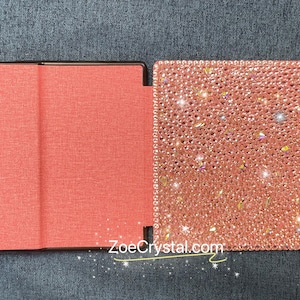May include: A pink and black book cover with a sparkly pink design. The cover is made of fabric and has a smooth texture. The text "ZoeCrystal.com" is printed on the cover.