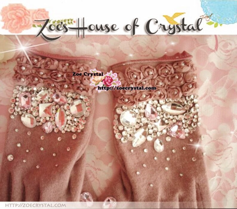 May include: A pair of pink fingerless gloves with a floral design and crystal embellishments. The gloves are made of a soft, fuzzy material. The text "Zoe's House of Crystal" and "Zoe Crystal" is visible on the image. The website address "http://zoecrystal.com" is also visible.