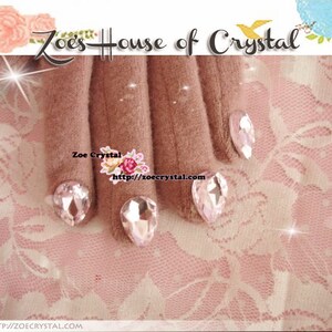 May include: Close-up of a hand wearing brown gloves with clear crystal rhinestones on each fingertip. The hand is resting on a pink lace fabric. The text "Zoe's House of Crystal" and "Zoe Crystal http://zoecrystal.com" is visible in the image.