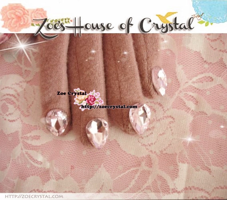 May include: Close-up of a hand wearing brown gloves with clear crystal rhinestones on each fingertip. The hand is resting on a pink lace fabric. The text "Zoe's House of Crystal" and "Zoe Crystal http://zoecrystal.com" is visible in the image.