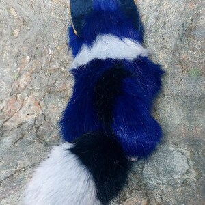 Puede incluir: Un juguete de peluche con forma de zorro de color azul, pecho blanco y cola negra y blanca.
