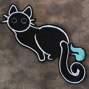 Op de afbeelding: Zwarte kat met een witte omtrek en een turquoise blauwe staartvlam. De kat zit op een bruine achtergrond.