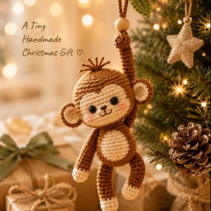 May include: A brown and cream crocheted monkey ornament with a small green leaf and wooden bead hanging from a string. The monkey has pink cheeks, black eyes, and a stitched mouth. Text on the image reads: A Tiny Handmade Christmas Gift.