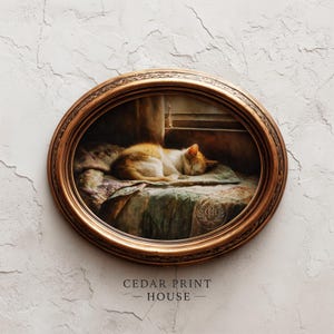 May include: Oval framed print featuring a sleeping orange and white cat on a patterned pillow. The artwork is set in a room with a window, framed by a detailed, ornate gold-colored frame. The text "CEDAR PRINT HOUSE" is at the bottom.