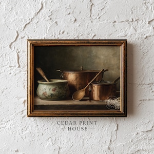 May include: A framed print featuring a still life of antique copper cookware and wooden spoons. A small, floral-decorated ceramic bowl is on the left. The print has a dark, moody aesthetic, with the text "CEDAR PRINT HOUSE" at the bottom.
