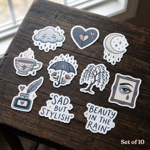 May include: A set of 10 stickers with a whimsical, melancholic theme. Designs include a crying cloud, a stitched heart, a crescent moon, a teacup, an umbrella, a weeping willow, an inkwell, and an eye. Text includes "SAD BUT STYLISH" and "BEAUTY IN THE RAIN".