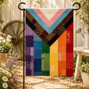 Könnte beinhalten: Eine rechteckige Gartenflagge mit einem Patchwork-Design und einem Chevron-Muster oben in Creme, Rosa, Blau und Braun. Der untere Teil besteht aus vertikalen Streifen aus violetten, blauen, grünen, gelben, orangen und roten Stoffquadraten.
