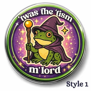May include: A round button with a green and purple design. The button features a cartoon frog wearing a wizard hat and cape, holding a staff. Text on the button reads "'twas the 'rism m'lord" and "Style 1".