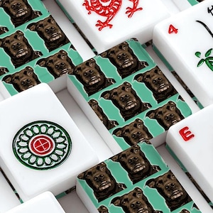 May include: A close-up of a set of white Mahjong tiles. The tiles feature various symbols, numbers, and Chinese characters in red, green, and black. The background is a repeating pattern of a dog's face on a teal background.
