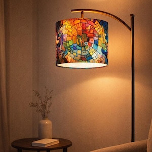 May include: A floor lamp with a stained glass lampshade. The lampshade features a colorful mosaic design with shades of red, orange, yellow, blue, and green. The lamp has a curved, gold-toned arm and a dark brown pole.