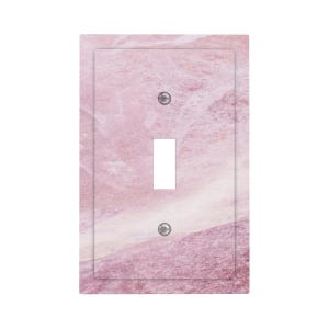 May include: A decorative light switch cover with a pink marble design. The cover has a rectangular shape with a single toggle switch opening and two screw holes. The marble pattern features shades of pink and white.