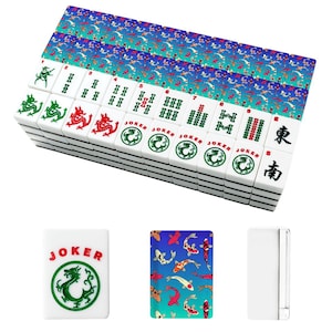 May include: A complete Mahjong set with white tiles featuring green and red dragon designs, Chinese characters, and the word "JOKER." The set includes colorful fish-patterned playing cards and a white case.