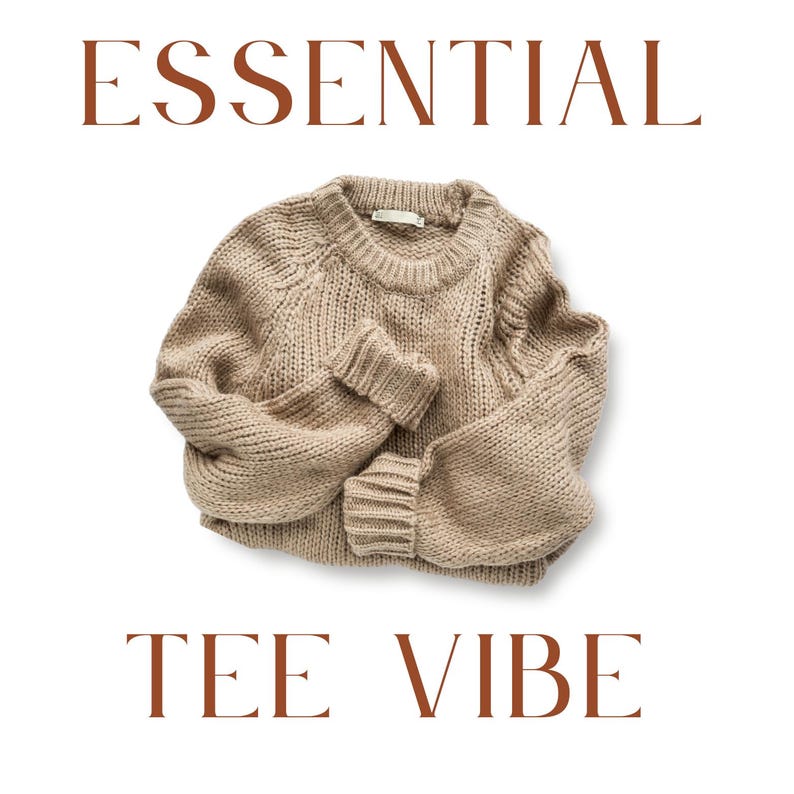 May include: A beige knit sweater with a crew neck and long sleeves. The sweater is made of a chunky knit material and has ribbed cuffs. The words "ESSENTIAL" and "TEE VIBE" are printed in brown.
