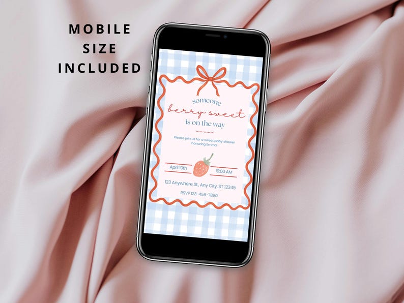 May include: A smartphone displays a baby shower invitation with a strawberry theme. The invitation features the text "someone berry sweet is on the way" on a light pink background with a blue gingham pattern. The phone is on a pink fabric.