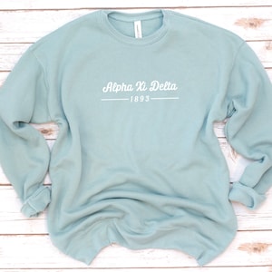 May include: A light blue sweatshirt with the text "Alpha Xi Delta 1893" in white.