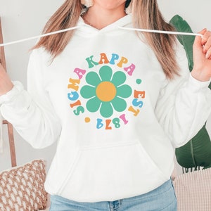 May include: White hooded sweatshirt with a colourful daisy and the text "Sigma Kappa Est. 1874" printed on the front.