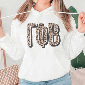 May include: White hooded sweatshirt with a leopard print Greek letter design that says "ΓΦΒ".
