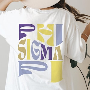 Könnte beinhalten: Weißes T-Shirt mit einem bunten Grafikdesign, das im Retro-Stil "PHI SIGMA PI" lautet.