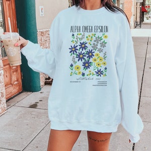 May include: White sweatshirt with a floral design and the text "Alpha Omega Epsilon established 1983 November 13 Friendship Leadership Professionalism".