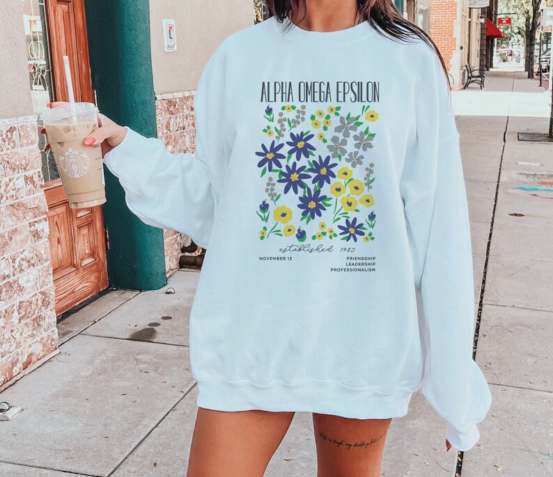 May include: White sweatshirt with a floral design and the text "Alpha Omega Epsilon established 1983 November 13 Friendship Leadership Professionalism".