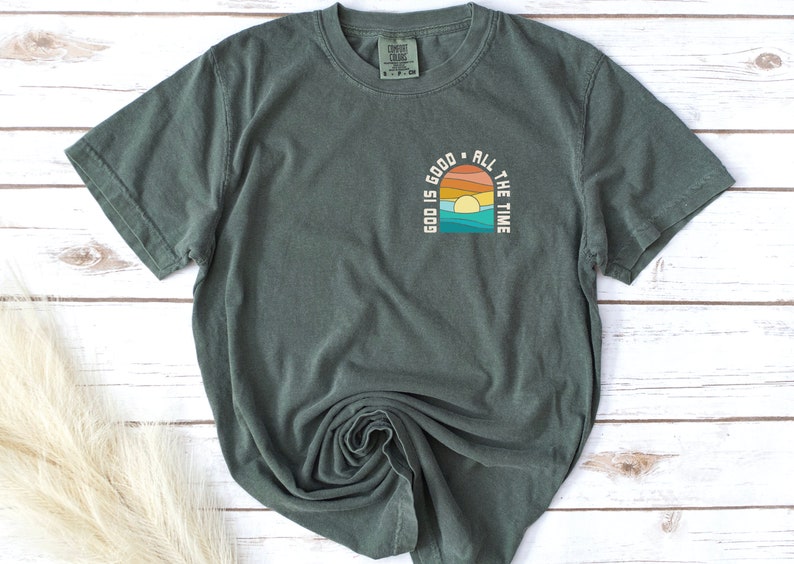 May include: A dark green t-shirt with a graphic print of a sunset and the text "Good is good all the time".