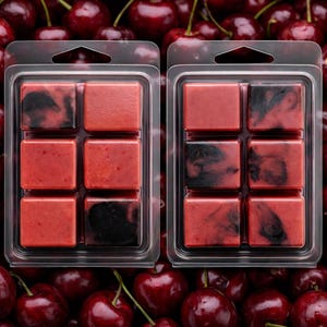 May include: Two clear plastic packs each holding six red wax melt cubes with black marbling. The wax melts are displayed on a bed of fresh, ripe cherries. The cubes are square and have a glossy finish.