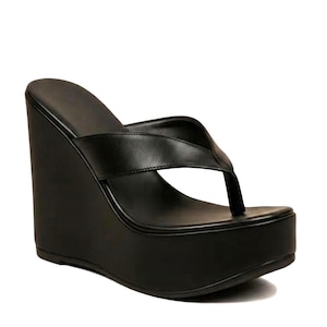 Könnte beinhalten: Schwarze Plateau-Keilsandalen mit Zehensteg-Design. Die Sandalen haben eine dicke Plateausohle und einen Keilabsatz. Die Schuhe sind aus einem glatten, einfarbigen schwarzen Material gefertigt.