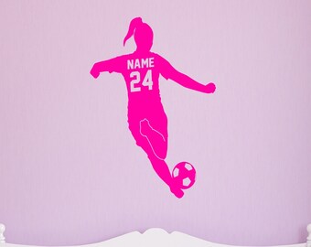 May include: Pink silhouette of a female soccer player kicking a ball with the text "NAME 24" on her jersey. The silhouette is on a pink wall above a white bed.