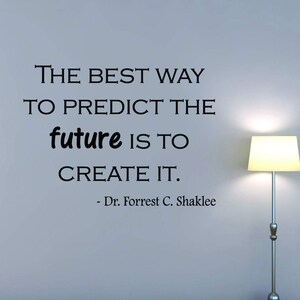May include: Black and white inspirational quote on a light blue wall. The quote reads "The best way to predict the future is to create it." - Dr. Forrest C. Shaklee.