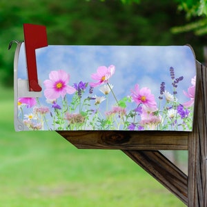 May include: A mailbox with a colorful floral design featuring pink, white, and purple flowers against a blue sky background.