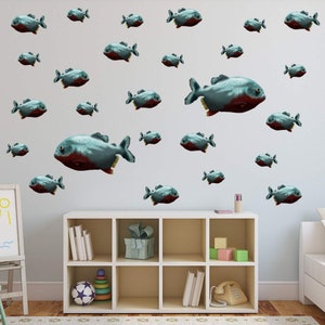 May include: A white wall with a variety of blue and red fish decals. The decals are arranged in a random pattern and are of varying sizes. The wall is in a room with a white bookshelf and a white easel.