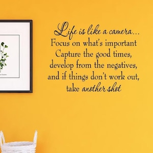 May include: A yellow wall with a framed botanical print and a white wall decal with the text "Life is like a camera... Focus on what's important Capture the good times, develop from the negatives, and if things don't work out, take another shot"