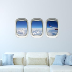May include: Three airplane window decals, each showing a view of clouds and blue sky. The decal on the right shows a red airplane wing.