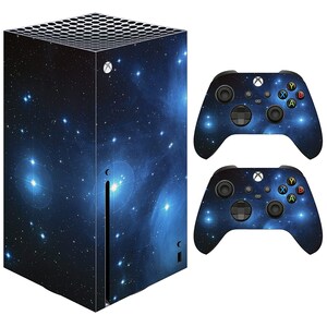 May include: A blue and black Xbox Series X console and two matching controllers with a galaxy design. The console and controllers feature a dark blue background with white stars and a nebula.