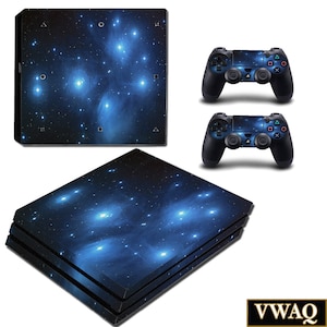 May include: A blue and black galaxy-themed skin for a Playstation 4 console and controller. The skin features a dark blue background with white stars and a nebula with bright blue and white highlights.