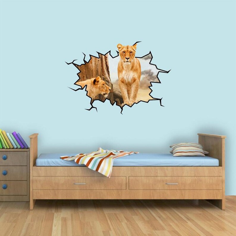 May include: A wall decal featuring two lionesses peeking out of a cracked wall. The decal is a 3D effect and appears to be breaking through the wall.