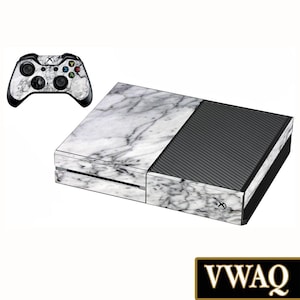 May include: A white and gray marble patterned skin for an Xbox One console and controller. The console has a black textured panel on the right side.