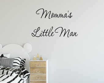 Op de afbeelding: Zwart-witte wanddecoratie met de tekst "Momma's Little Man" in een cursief schrift.