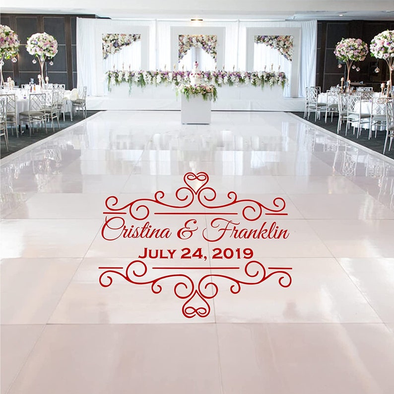 May include: A white dance floor with a red decorative sticker that says "Cristina & Franklin JULY 24, 2019" with a heart and swirls.