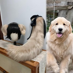 May include: A wig with black hair and tan ears, a tan faux fur tail with a black ribbon, and a Golden Retriever dog. The wig and tail are displayed on a wooden surface. The dog is light tan with a pink tongue.