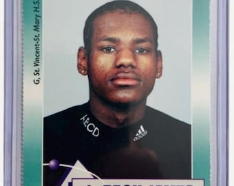 May include: A sports trading card featuring a portrait of LeBron James wearing a black shirt with an Adidas logo. The card has a teal border, the text RR, G, St. Vincent-St. Mary H.S., and the website www.rookiereview.com printed on the front.
