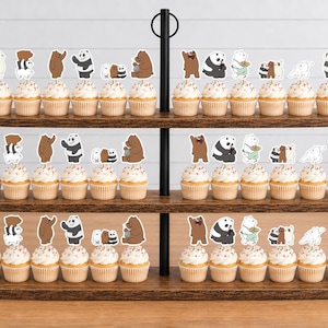 May include: A three-tiered wooden cupcake stand holding numerous cupcakes topped with various cartoon bear character paper toppers. The bears are depicted in different poses, including standing, sitting, and grouped together, featuring brown, white, and panda designs.