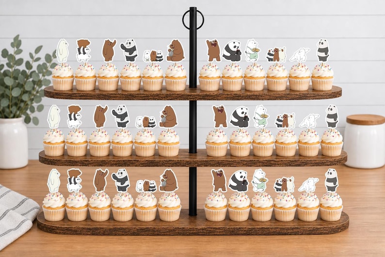 May include: A three-tiered wooden cupcake stand holding numerous cupcakes topped with various cartoon bear character paper toppers. The bears are depicted in different poses, including standing, sitting, and grouped together, featuring brown, white, and panda designs.