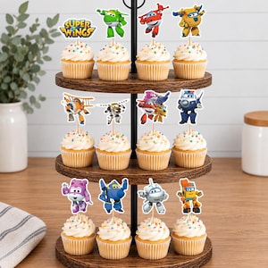 K&ouml;nnte beinhalten: Ein dreist&ouml;ckiger Cupcake-St&auml;nder aus Holz mit zw&ouml;lf Cupcakes, die mit wei&szlig;em Zuckerguss und bunten Streuseln verziert sind. Jeder Cupcake hat einen Super Wings-Figurenaufstecker aus Papier auf einem Holzspie&szlig;, darunter Jett, Donnie, Dizzy und Paul.